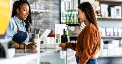 Young woman using credit card reader at coffee shop counter