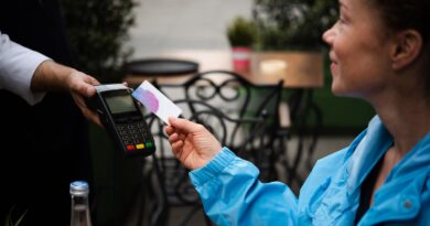 Happy young woman paying for her coffee by a credit card