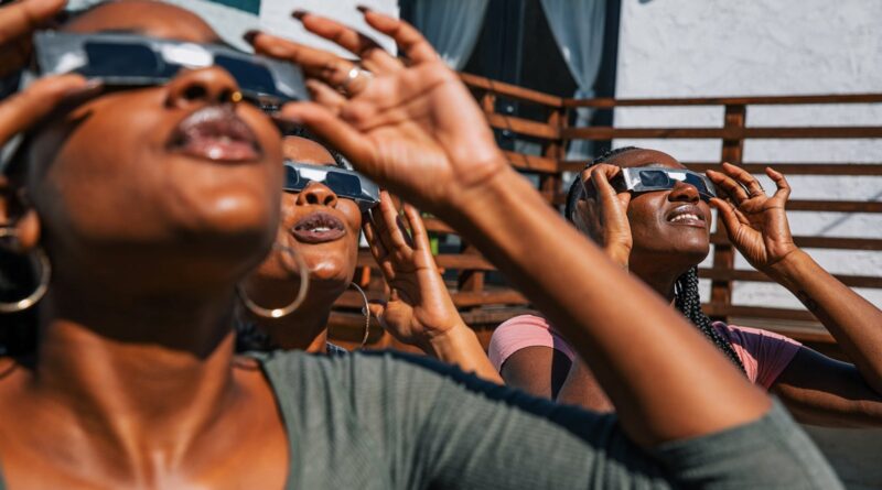 Women friends at home enjoying solar eclipse looking at the sun with eclipse sunglasses