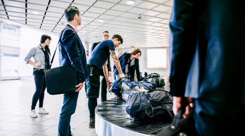 Group of travellers waiting for their luggage at baggage claim