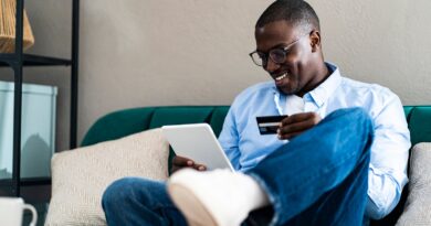 Smiling man paying through credit card while using digital tablet at home