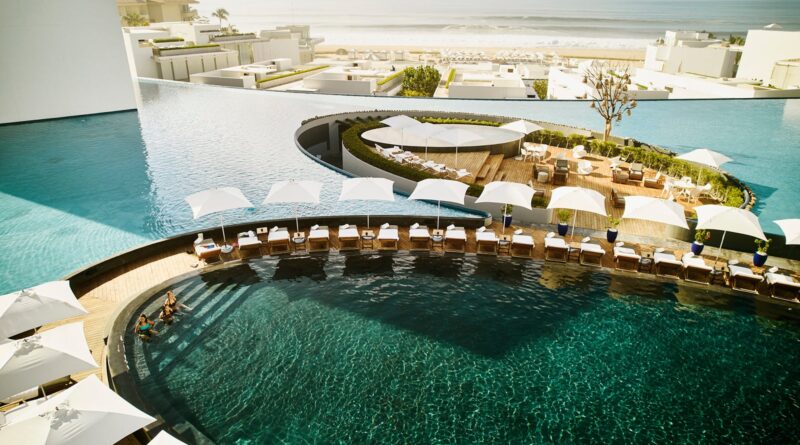 Wide shot aerial view of family relaxing in pool at tropical resort