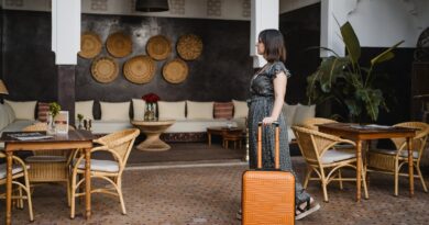 side view of young woman with an orange suitcase in the hotel