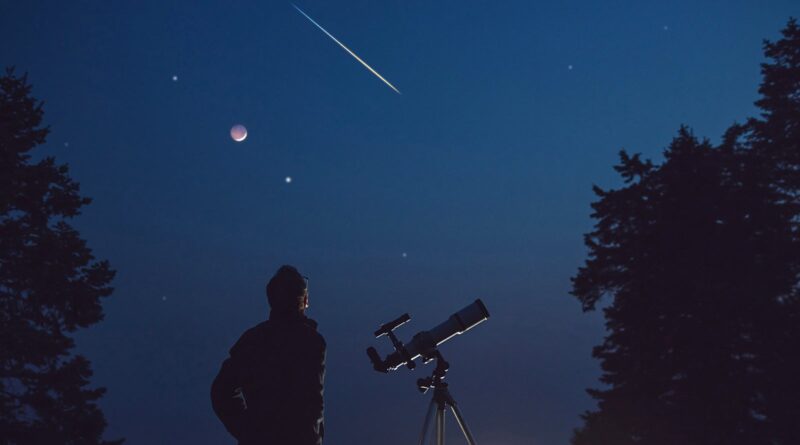 Silhouette of a man, telescope, stars, planets and shooting star under the night sky.