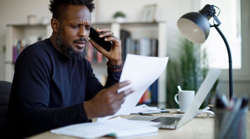 Worried man talking on the phone while working from home